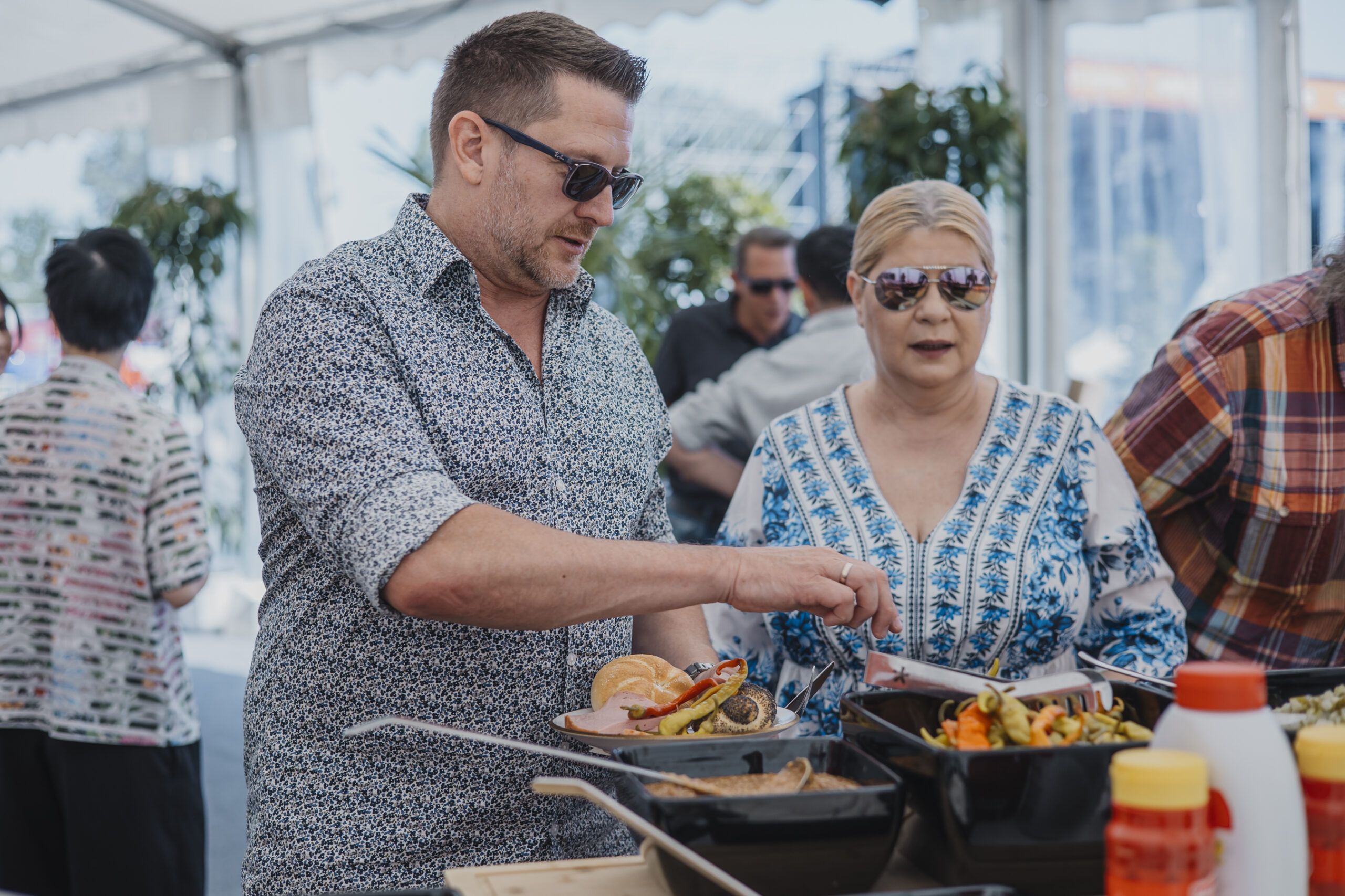 EIn Mann und eine Frau stehen vor dem Leberkäs Buffet.