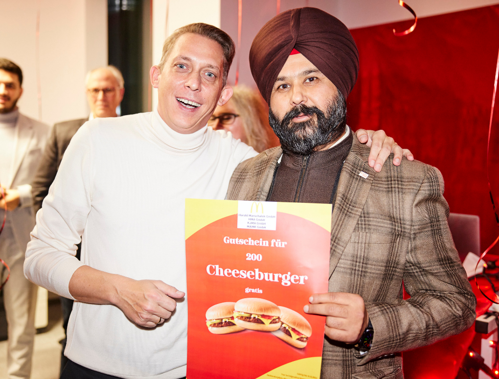 Harald Marschalek und Gurdial Singh Bajwa halten ein Mcdonalds Gutschein für 200 Cheeseburger. 