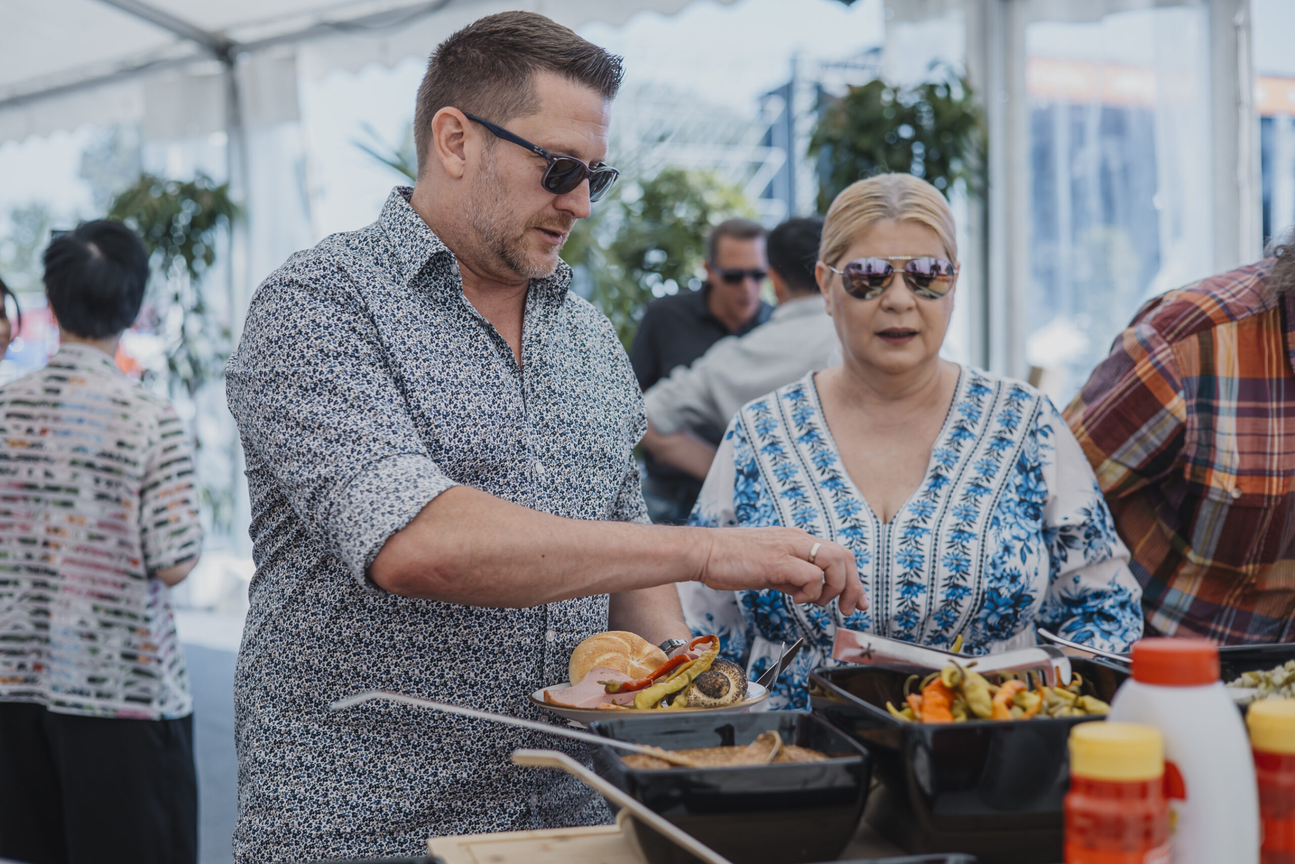 EIn Mann und eine Frau stehen vor dem Leberkäs Buffet.