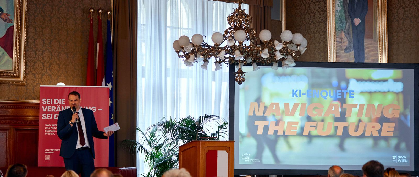 Mann steht neben Leinwand mit der Überschrift "KI-Enquete: Navigating the Future".